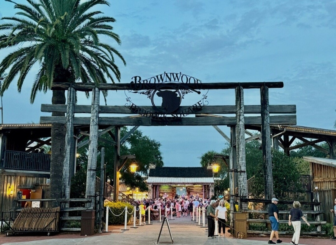 Brownwood Paddock Square in The Villages, Florida at dusk — palm trees, lantern light and an evening crowd gathered for live music